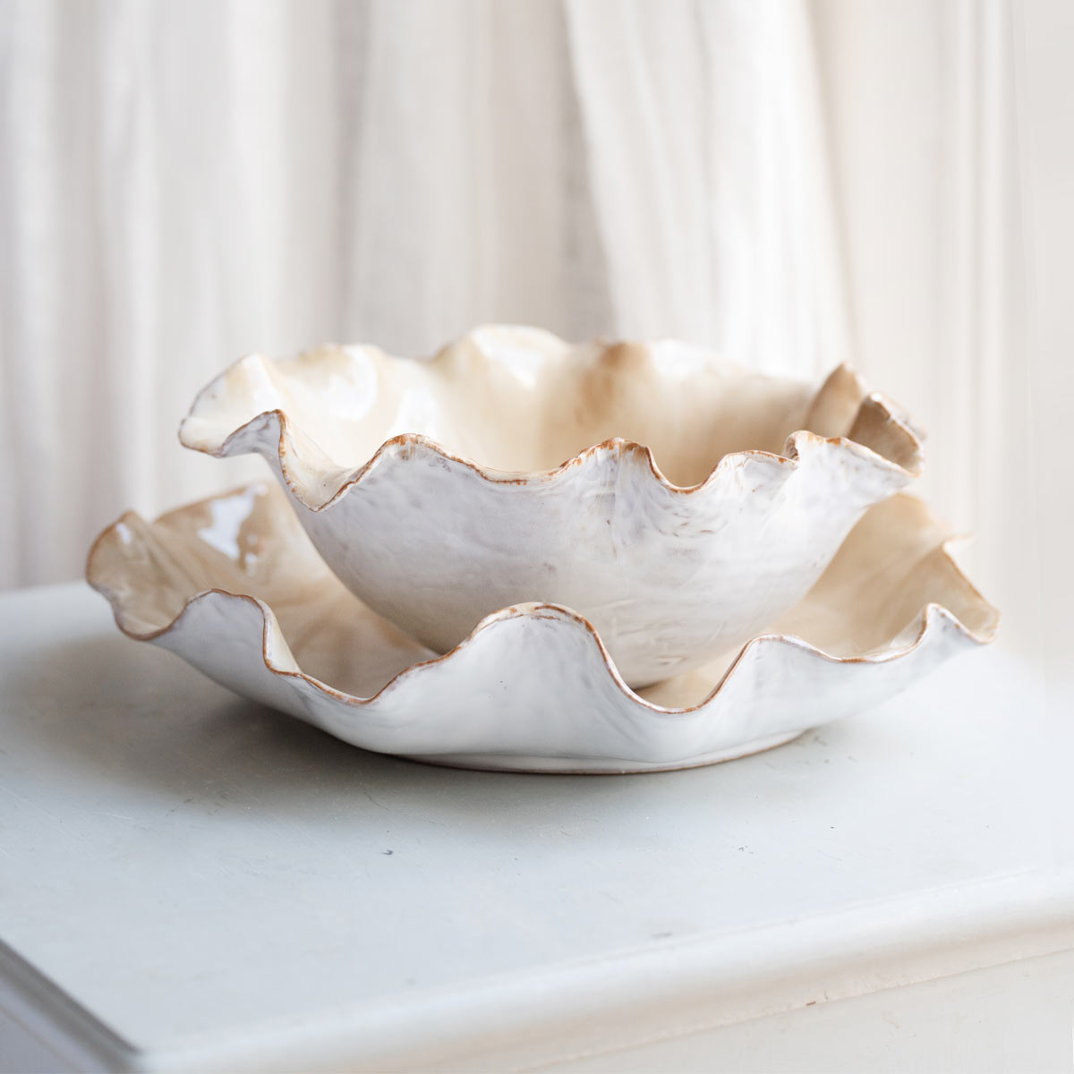 Juliette Petal-Edged Porcelain Bowl displayed on Juliette saucer. Displayed on cream table with cream background.