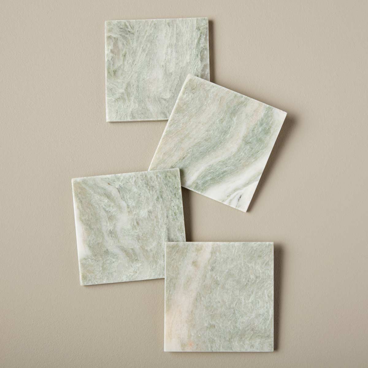 A set of four handcrafted Lady Onyx marble coasters with natural green and pink veining, ethically sourced from Agra, India.