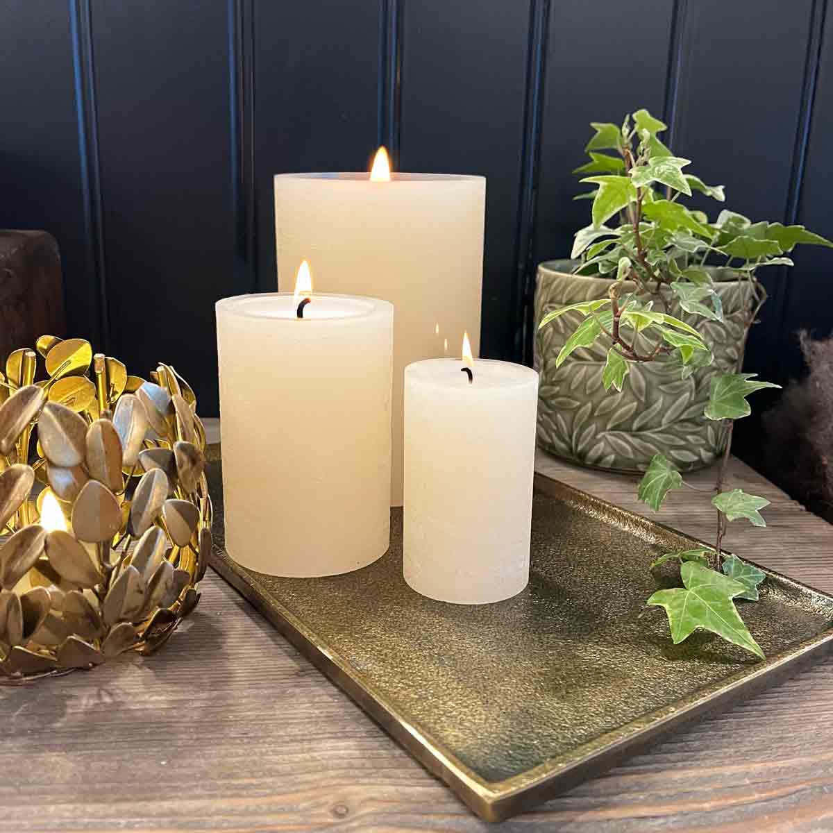 Maes Rectangle Candle Plate in Antique Bronze, styled with pillar LED candles, a gold tealight holder, and greenery on a wooden table.