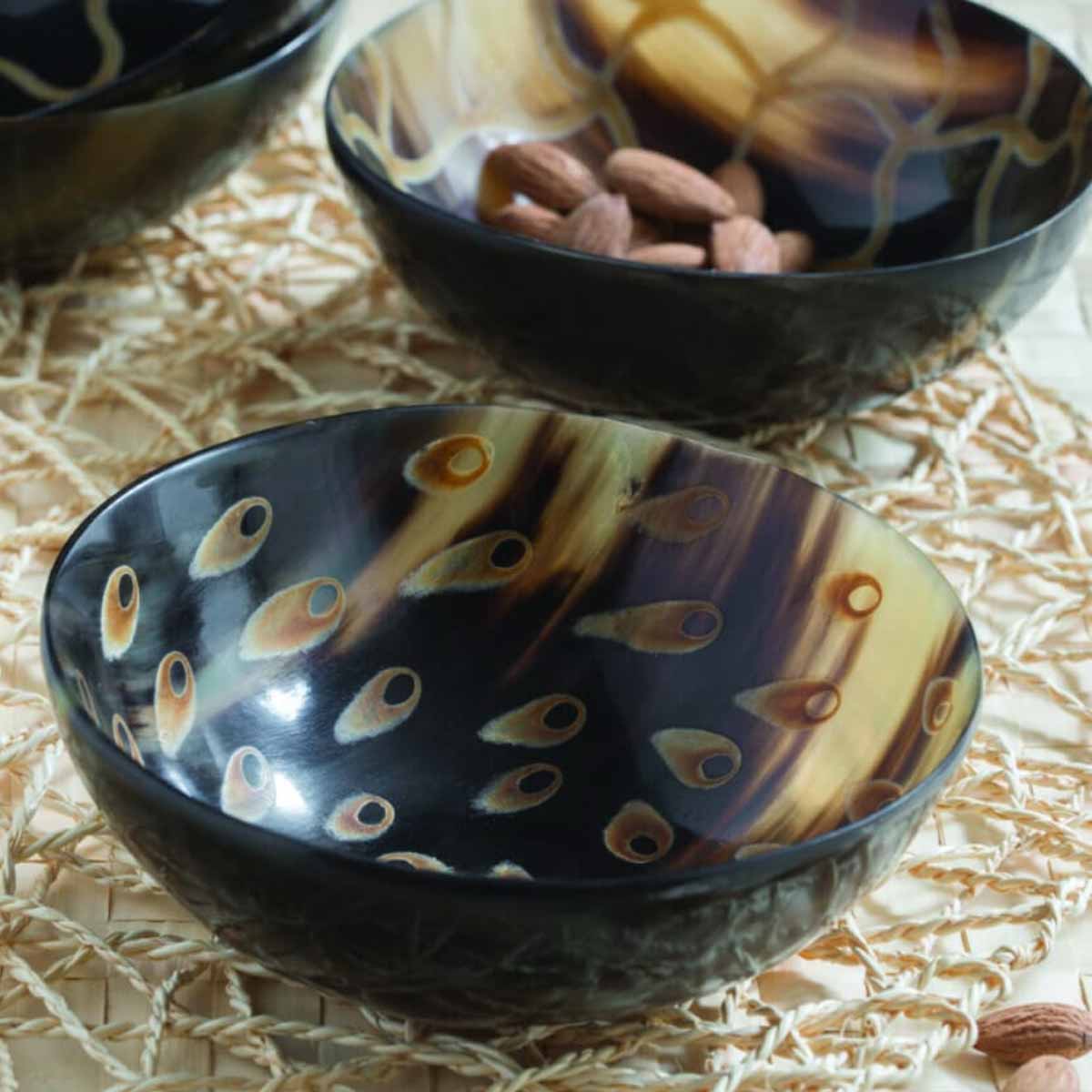 Handcrafted Peacock Horn Bowl - Small, featuring an intricate hand-painted peacock feather design on ethically sourced water buffalo horn, made in Vietnam - displayed on table with nuts.