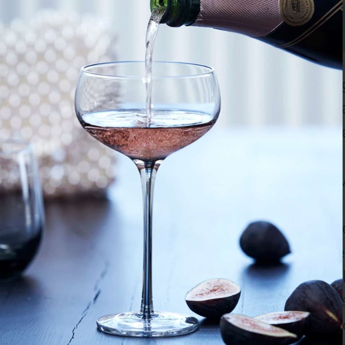 Elegant smoked cocktail glass, mouth-blown with a solid colour finish, displayed with pink moet champagne being poured.